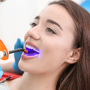 A young woman receiving dental care with an electric toothbrush during a teeth cleaning session.